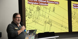 A person standing at a podium holding a microphone and talking